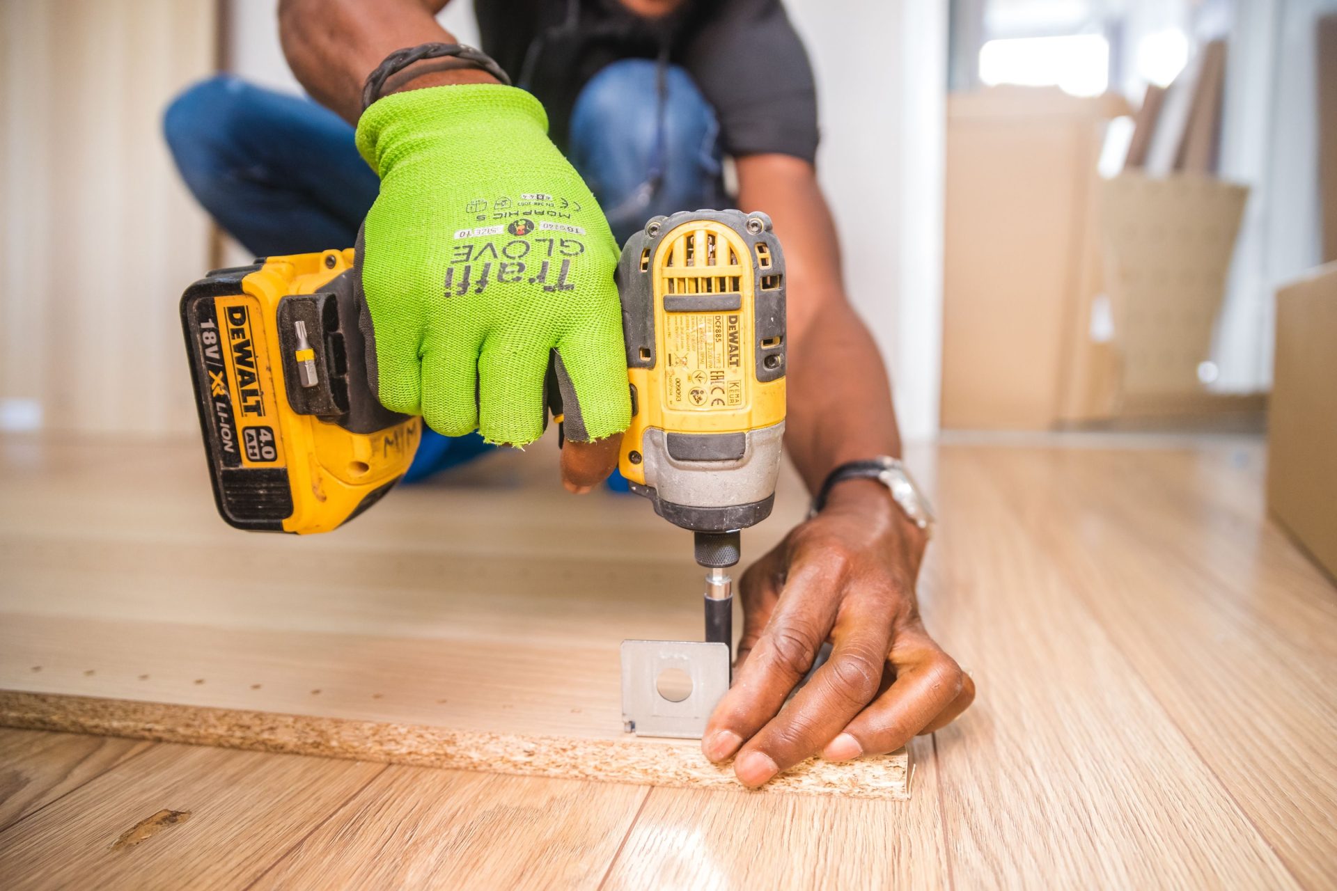 Ein Mann verwendet präzise eine Bohrmaschine für Heimwerkerarbeiten an einem Holzboden.