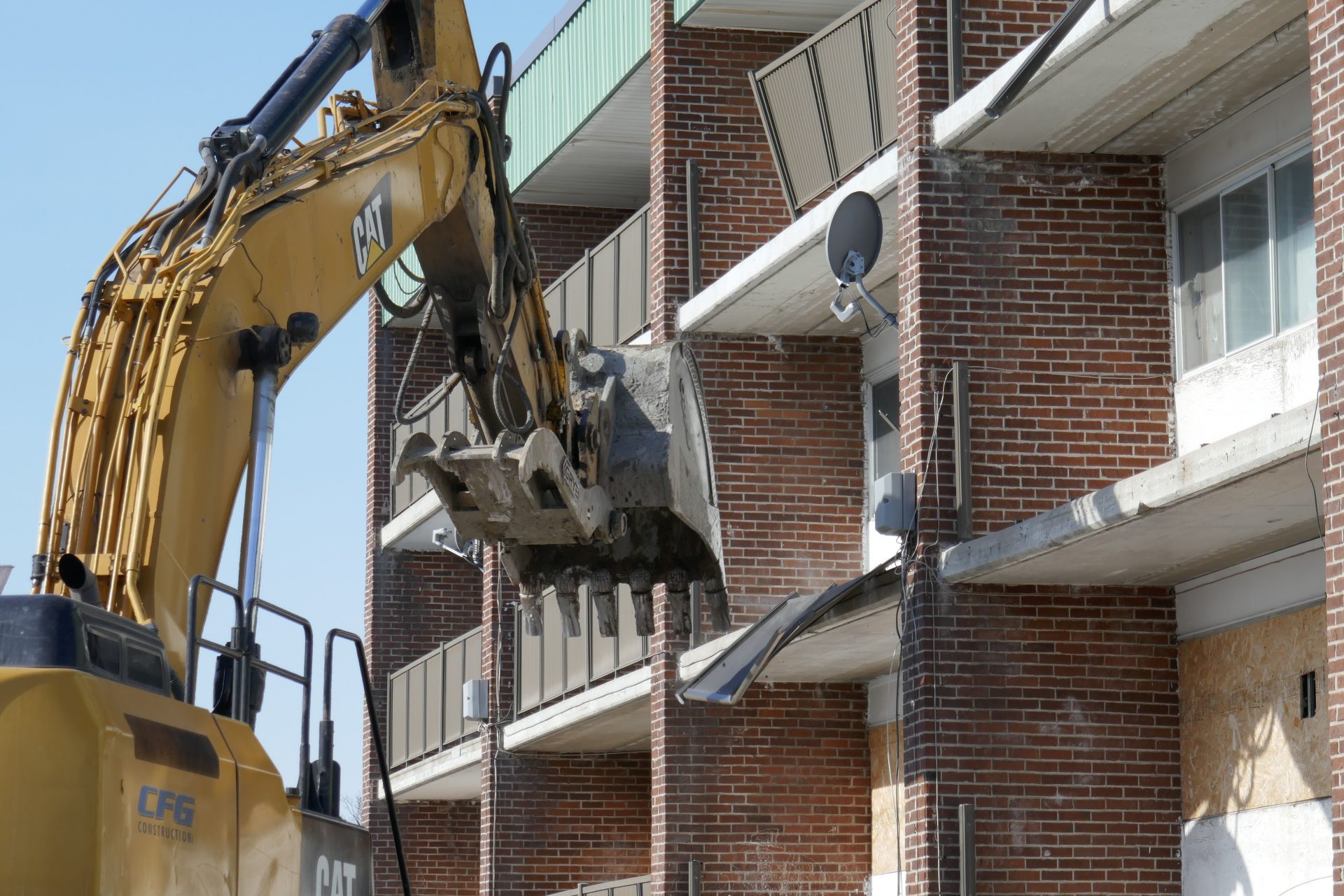 Ein Bagger reißt ein Wohngebäude aus Ziegelmauerwerk in einem städtischen Gebiet ab.